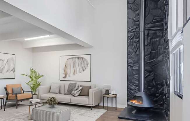 A modern living room with a grey sofa, a coffee table, a fireplace, and a painting on the wall.