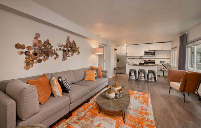 A living room with a grey couch and orange pillows.