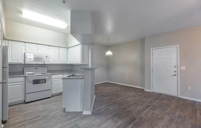 an empty kitchen and living room with white appliances and white cabinets