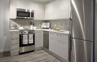 a small kitchen with stainless steel appliances and white cabinets at 1305 Dock Street, Maryland