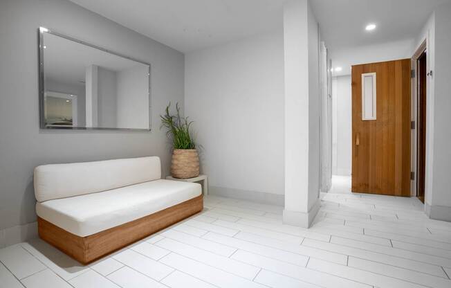 A white couch sits in a room with a mirror above it.