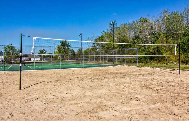 A sandy beach volleyball court with a net and posts.