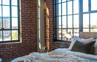 a bedroom with large windows and a bed in front of a brick wall at The 22 Apartments, Missouri