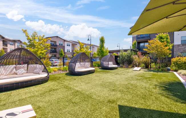 a backyard with lounge chairs and a grassy area with apartment buildings in the background