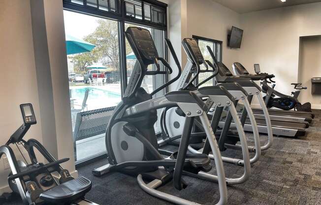 a row of treadmills and elliptical trainers in a gym