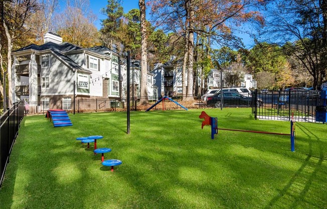 a grassy area with a playground and houses in the background