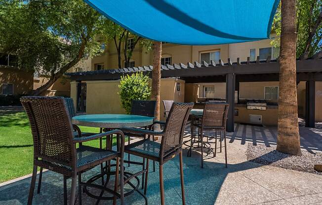 A patio with a table and chairs under a blue umbrella.at Palazzo Townhomes, Phoenix, 85008  