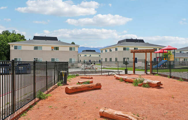 A playground with a red swing set and a black fence.