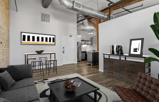 A modern living room with a grey couch, a black coffee table, and a brown leather chair.
