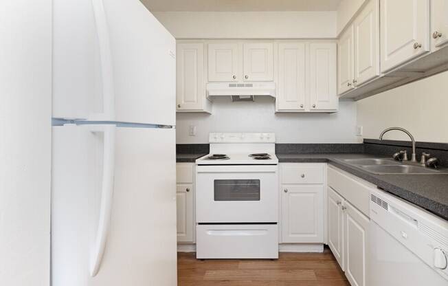 A white kitchen with a refrigerator, stove, and cabinets.