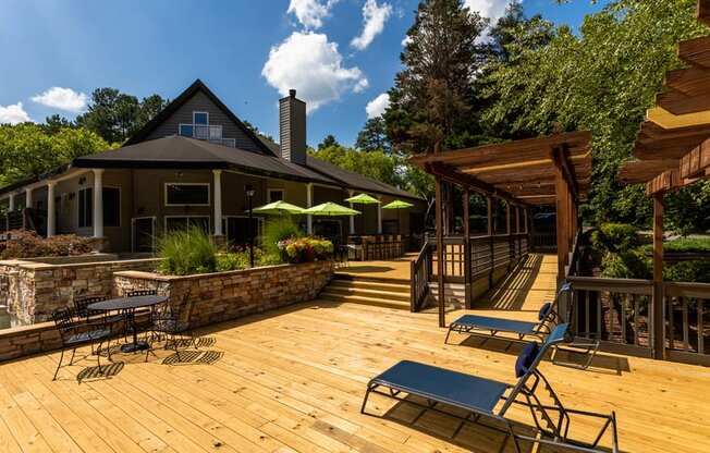 a large deck with chairs and umbrellas in front of a house