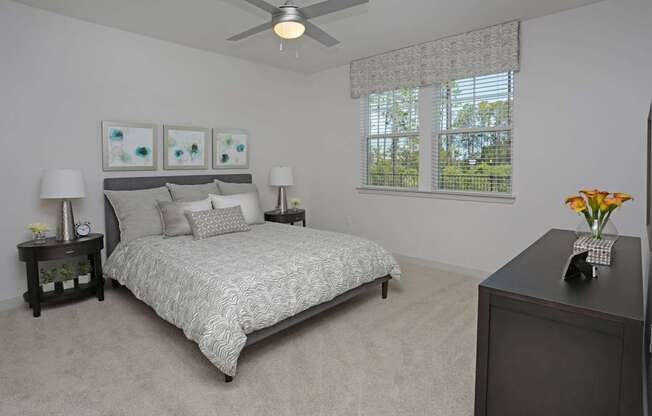 A bedroom with a large bed, two lamps, and a ceiling fan.