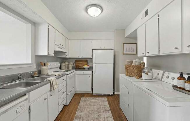 A white kitchen with a refrigerator, sink, and oven.