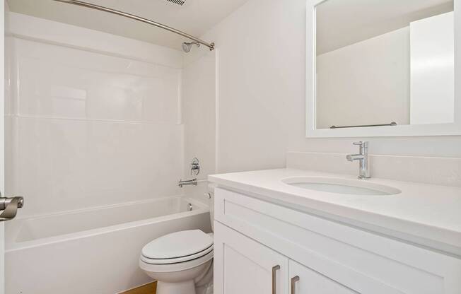 A white bathroom with a toilet, sink, and bathtub.