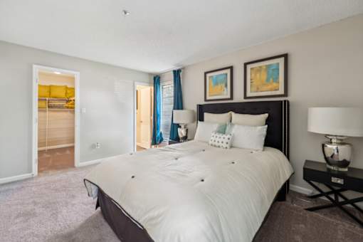 A bedroom with a large bed and a nightstand with a lamp.