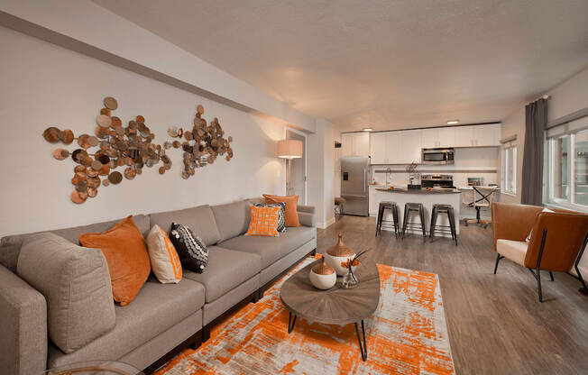 A living room with a grey couch and orange pillows