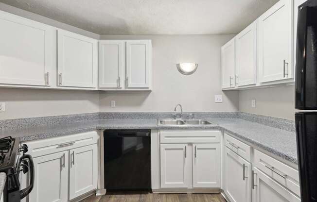 A kitchen with white cabinets and black appliances at Gwinnett Square Apartments in Duluth, GA