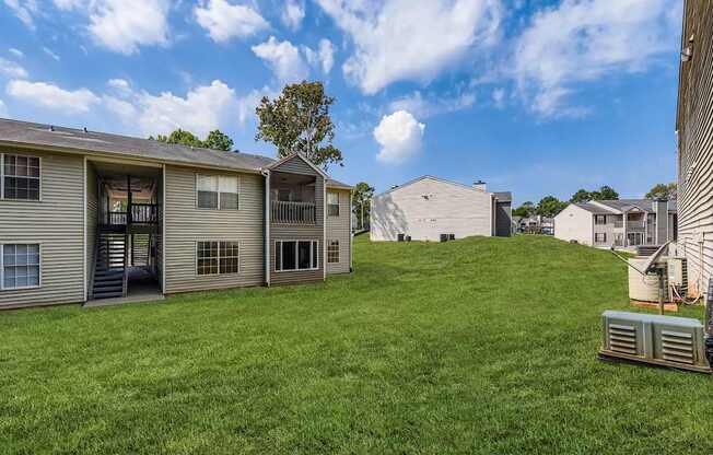 A sunny day at a grassy apartment complex with a few trees.