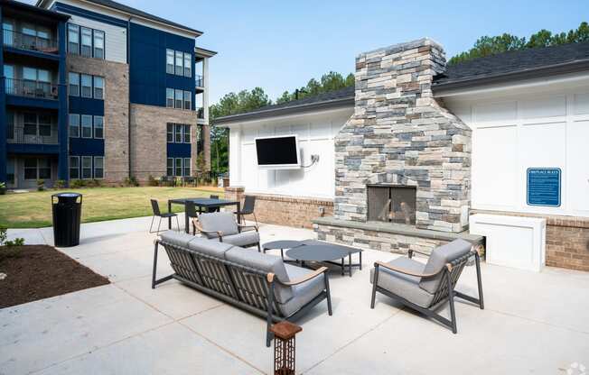 an outdoor patio with furniture and a stone fireplace at Preston Ridge, Cary, 27513