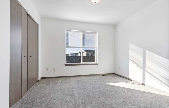 A room with a window and a grey carpet.