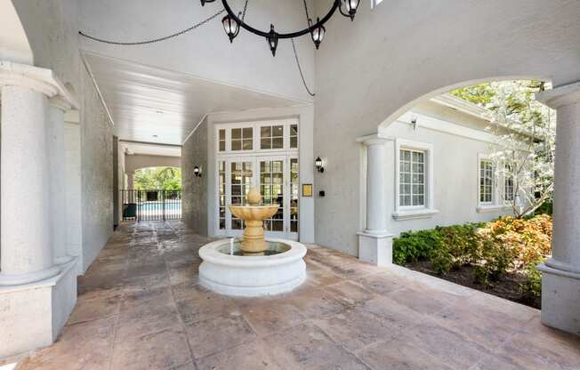 a courtyard with a fountain in the middle of a white house