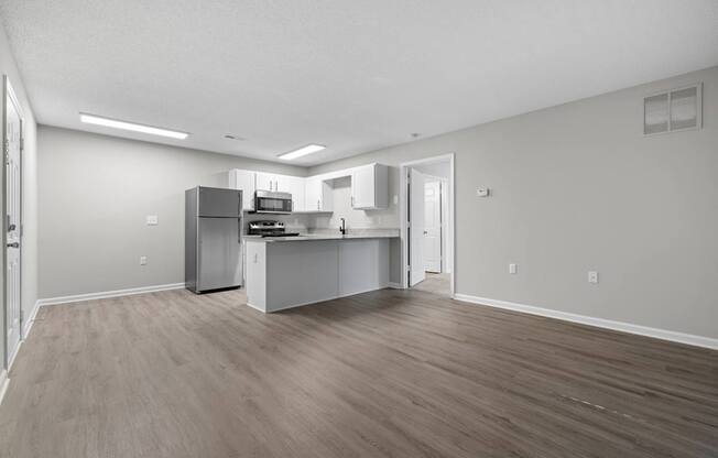 A kitchen with a refrigerator, microwave, and oven.