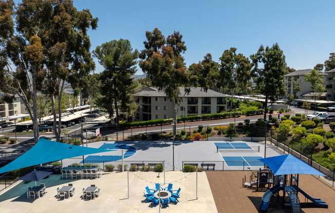 an aerial view of an outdoor pool with blue umbrellas and tables and buildings