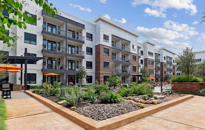 A modern apartment complex with a landscaped courtyard in front.