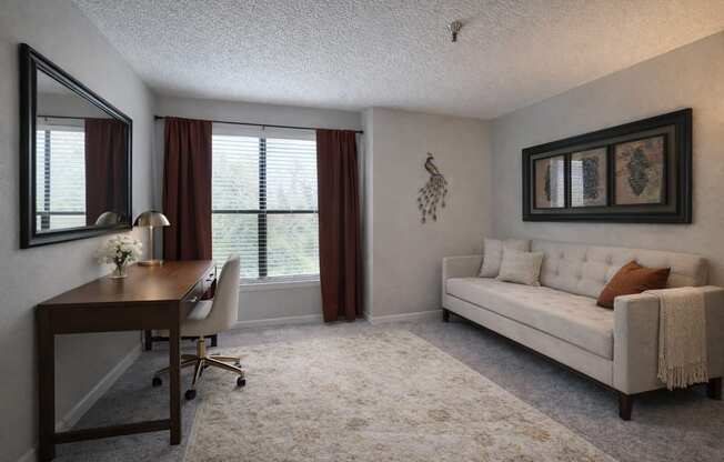 A well-lit room with a desk, chair, and couch.