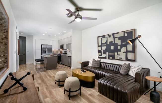 A living room with a brown leather couch and a ceiling fan.