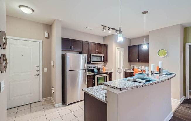 A kitchen with a granite counter top and stainless steel appliances.