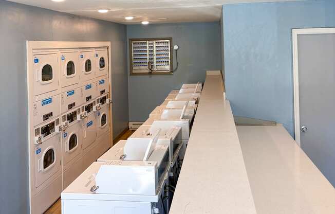 A laundry room with rows of washing machines.
