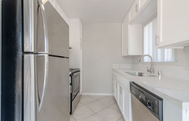 a kitchen with white cabinets and a stainless steel refrigerator at Citra Apartments LLC, California