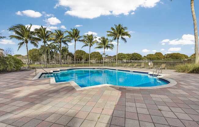 A swimming pool surrounded by palm trees and a tiled floor.