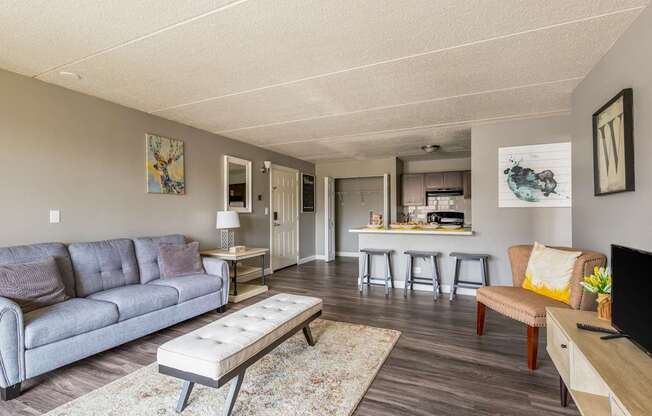 A living room with a grey couch and a wooden bench.