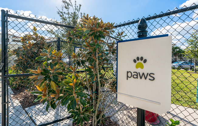 View of Dog Park, Showing Fenced-In Dog Park and Paws Signage at The Marq Highland Park Apartments