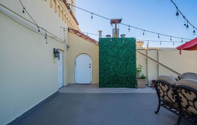 A patio with a wall of green plants and a white door.