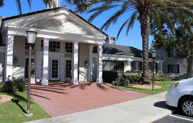 A white house with a black roof and a car parked in front.