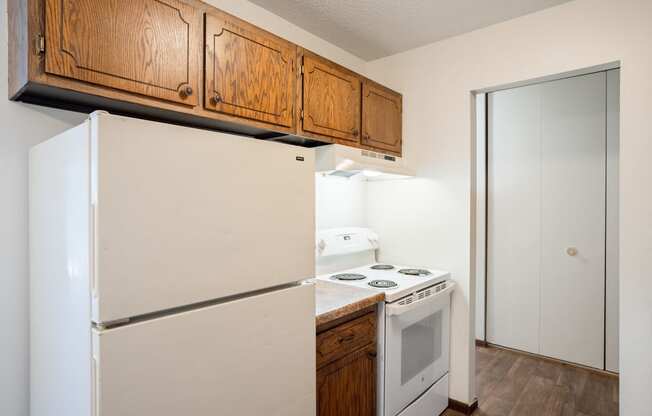 a kitchen with white appliances and wooden cabinets and a refrigerator. Eagan, MN Glen Pond Apartments