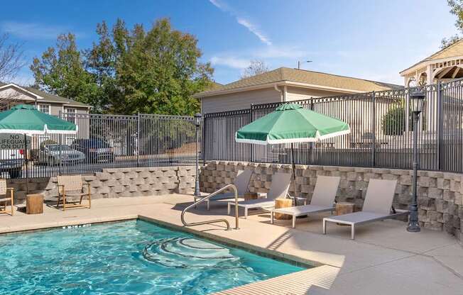 A pool with a stone wall and a fence.