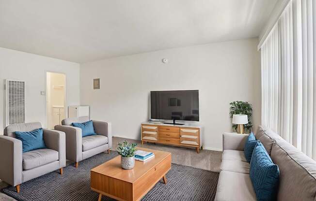A living room with a grey couch, a wooden coffee table, and a television on a wooden stand.