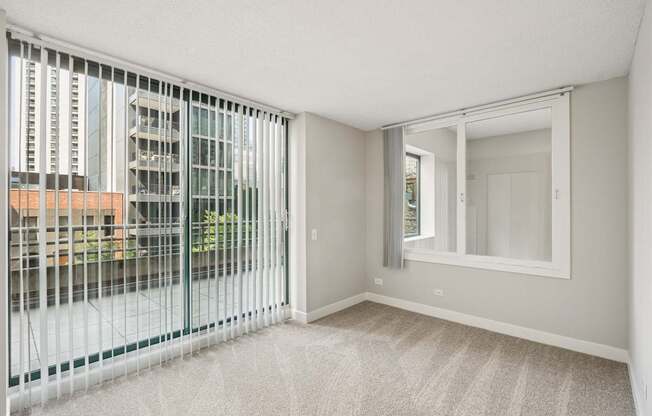 A room with a carpeted floor and a large window with a view of a cityscape.