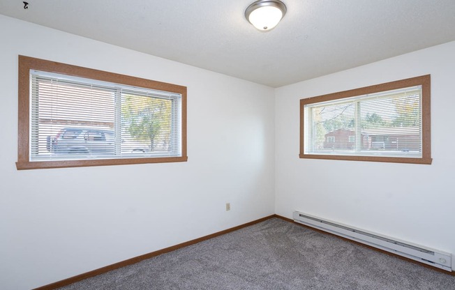 a bedroom with two windows and a carpet. Fargo, ND Pacific South Apartments