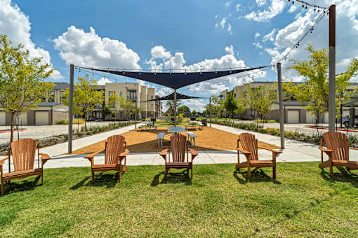A shaded outdoor seating area with wooden chairs.