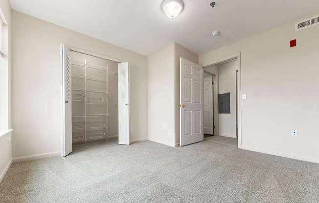A bedroom with a carpeted floor and a walk-in closet with wardrobe organizers at Fieldstream Apartment Homes in IA 50023