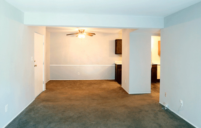 an empty room with a carpeted floor and a ceiling fan