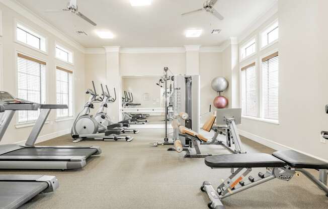 a gym with cardio equipment and weights on the floor