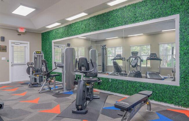 a gym with exercise equipment and a wall of grass