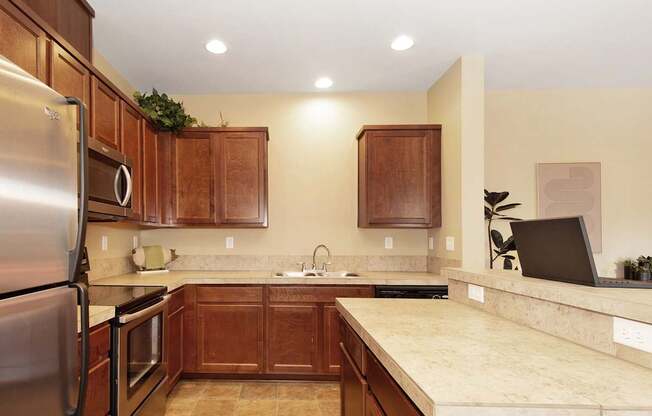 A kitchen with wooden cabinets and a tan countertop at The Landing Apartments and Townhomes, Oregon, 97045