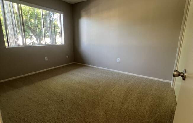 an empty bedroom with a large window and carpet